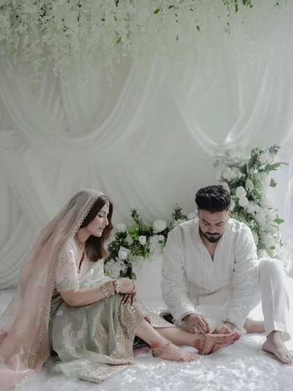 A tender moment between the couple, set against a backdrop of cascading white wisteria and soft drapery. The design is layered and textural, creating a visually rich yet calming environment.