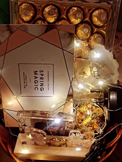 A closer look inside a custom gift hamper, featuring resin art coasters, chocolates, and other curated items.