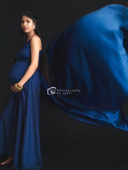 A wide-angle shot showcasing a flowing blue gown against a black background, creating a dramatic and powerful image.