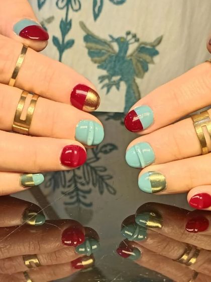 A bold and modern design with color-blocked red and teal nails, accented with a metallic gold stripe.
