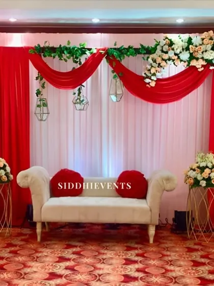 A classic and passionate color scheme of red and white. The elegant white diwan with red cushions is set against draped curtains and a beautiful floral arch.