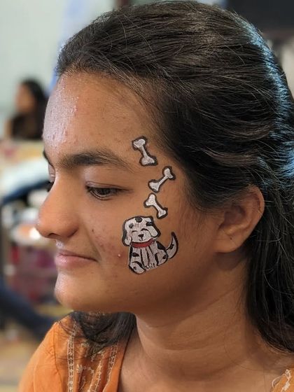 A cute Dalmatian puppy with bones painted on a girl's cheek, a fun design for any dog lover.
