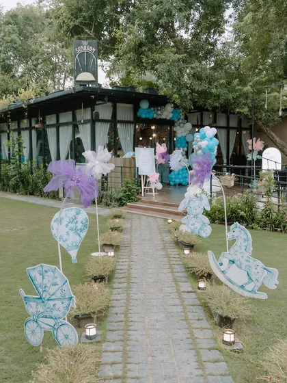First impressions matter, and this Dior-inspired entrance sets a tone of outdoor elegance. The landscaped walkway is lined with custom cutouts of rocking horses and prams, leading guests toward a beautiful celebration under the trees.