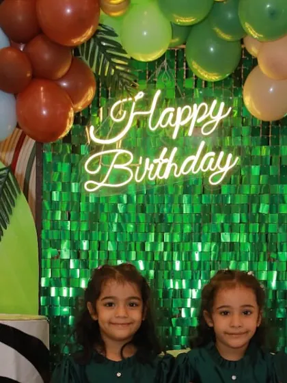 A wild Madagascar-themed birthday bash for adorable twins. The setup includes a lush green sequin backdrop and character appearances, transporting everyone to the world of Alex the Lion and his friends.