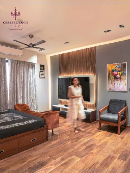 A bedroom featuring an earth-brown slatted wall behind the TV, ash grey accents, and warm wooden flooring.