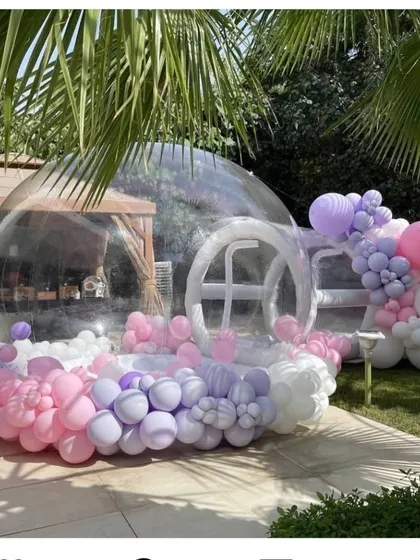 Our bubble house is a magical attraction for any outdoor party. Filled with balloons, it creates a unique photo opportunity and a whimsical play space for kids and adults alike, shown here at a garden party.