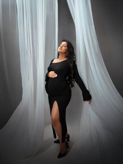 A powerful and serene pose. The mom to be looks radiant and confident, surrounded by ethereal white curtains in this fashion forward maternity shoot.