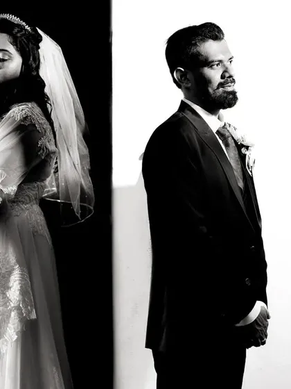 A simple black and white portrait using a split background to create a strong graphic element. This composition adds a modern, artistic feel to a classic couple portrait, focusing on their individual presence.