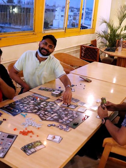 A game of Clank! in Space with a view of the city. It's a unique gaming experience you can only get at Dialogues.