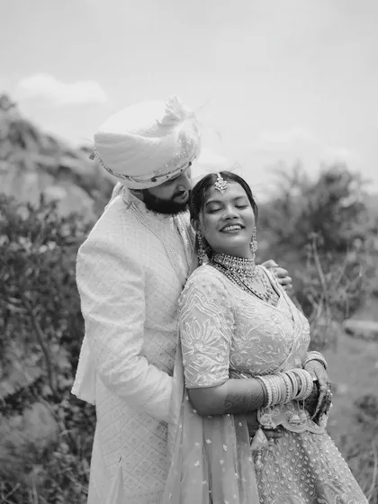 A classic black and white portrait of the couple in a natural setting, her smile radiant as he holds her close.