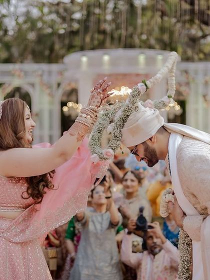 The bride playfully trying to put the garland on the groom.