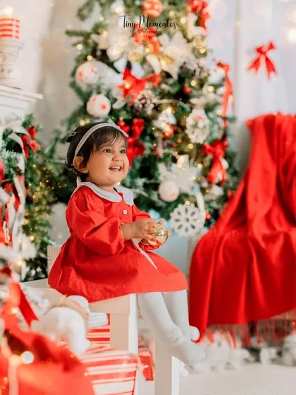 A candid moment of wonder. This little girl is captivated by a Christmas ornament, creating a beautiful and authentic holiday memory.