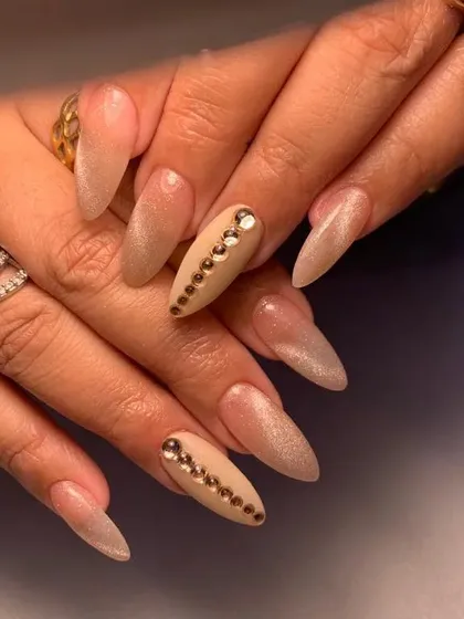 A glamorous set of long, nude-toned stiletto nails with a line of crystals down the center of the accent nails.