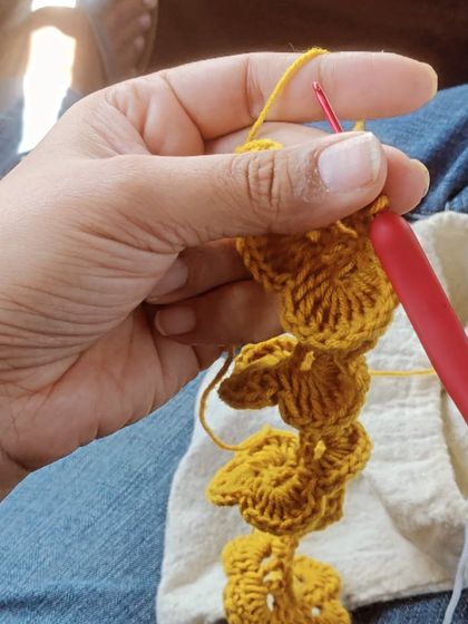 A close-up of my hand holding the crochet hook while working on the yellow flower. It's my happy place, creating something beautiful wherever I am.
