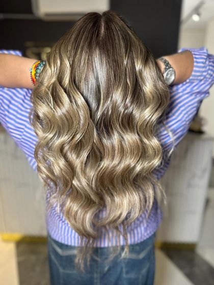 Seamlessly blended ashy blonde tones create a sophisticated and modern look, shown here with beautiful waves.