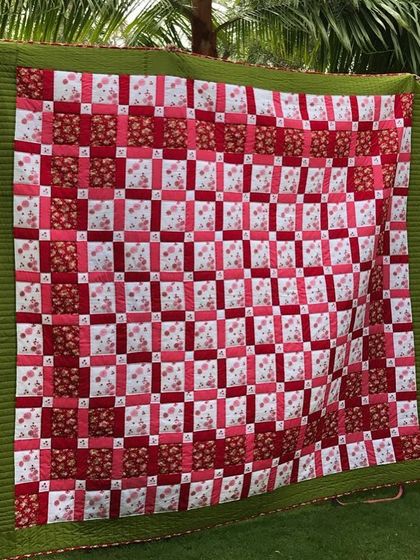 A classic Irish Chain quilt in red and white, displayed outdoors.