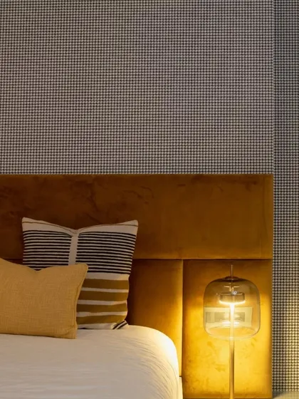 A close-up of the master bedroom in the Mulund project. I modified the existing bed with a bright mustard headboard and used a classic houndstooth wallpaper to add drama and personality.