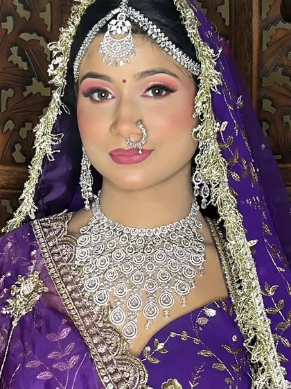 A bride in a purple saree with a stunning, multi-layered American Diamond necklace and mathapatti. This is a grand and royal look for a reception.