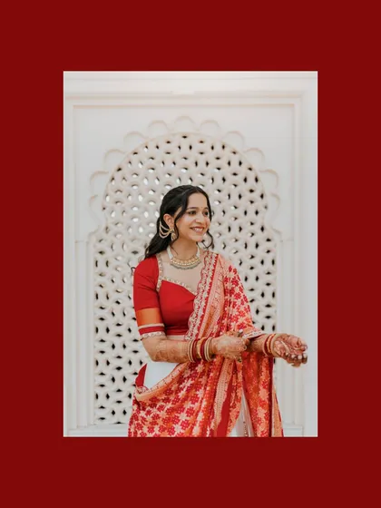 A beautiful bridal portrait against an intricate white jali screen. The red border frames the image, making the bride's elegance and her stunning outfit the central focus.
