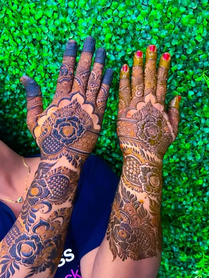 A vibrant shot of a heavy floral design against a green background, showing the beautiful contrast of the dark henna paste.
