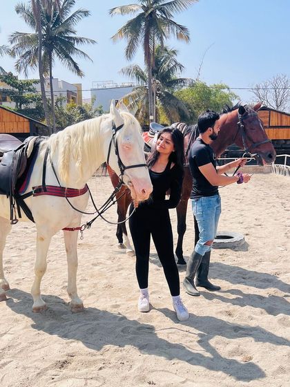 A rider shares a quiet moment with a white horse while another is being prepared for a lesson. It's a typical day filled with love for horses.