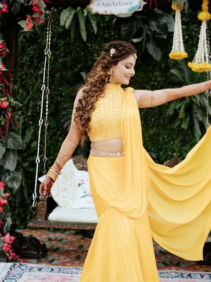 The bride showing off her beautiful pleated yellow saree, a modern and elegant choice for a Haldi ceremony.