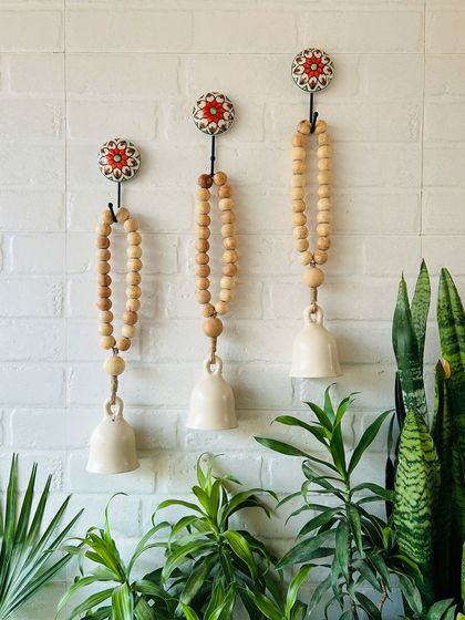 For a rustic and bohemian touch, our classic white boho beaded ceramic bells are a perfect choice. This image shows a set of three, strung with natural wooden beads and jute twine, hanging from our hand-painted ceramic hooks.
