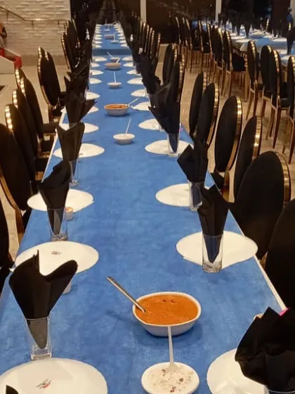 We believe a great meal starts with a beautiful setting. This is an example of our elegant seated dinner arrangement for a large event, with meticulous table settings ready to welcome guests for a formal feast.