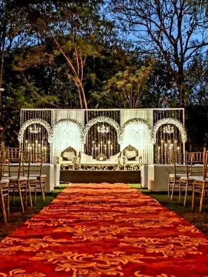A dramatic red carpet leads to an elegant white and gold stage, creating a grand and formal aisle for a wedding reception.