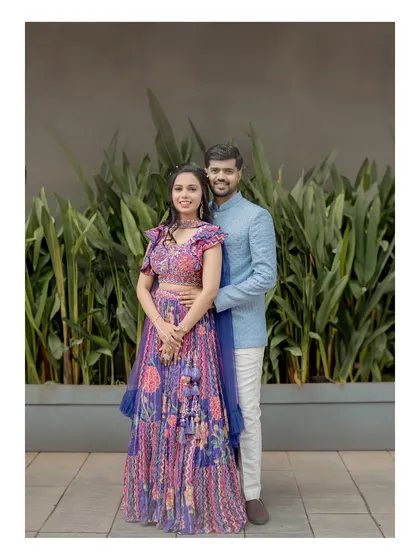 A classic couple portrait from their Sangeet or reception. They look happy and elegant against the simple, modern backdrop.