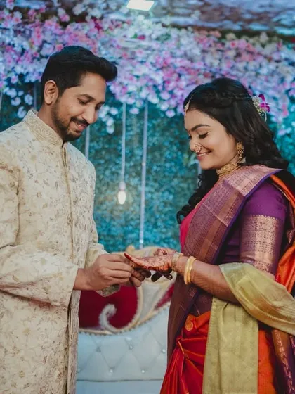 A wider shot of the ring exchange, showing the beautiful floral backdrop and the couple's interaction. This provides context and captures the ambiance of the event.