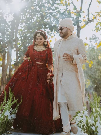 The couple walks together through a sunlit path, a beautiful candid moment from their wedding day.