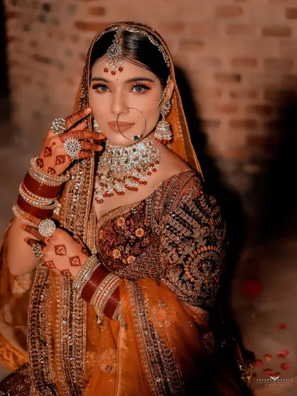 A powerful portrait of the bride looking directly at the camera, showcasing her striking eyes and detailed henna design.