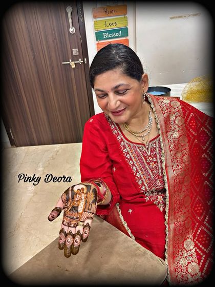 A happy client showcasing her Karwa Chauth mehndi. The design features a beautiful couple portrait, symbolizing the love and bond that this festival celebrates.