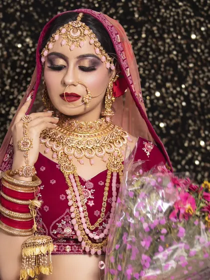 A bride in a deep pink lehenga adorned with a matching pink-beaded Kundan jewellery set, complete with kalire. This shows a full, ready-for-the-ceremony look.