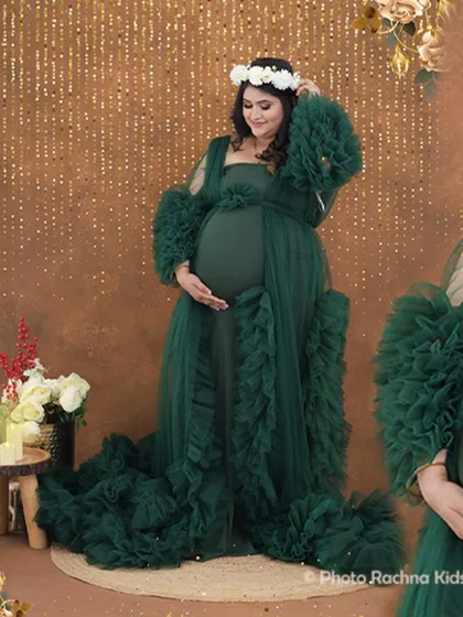 A full-length portrait showcasing a gorgeous green ruffled gown against a sparkling gold backdrop. The floral crown adds a soft, bohemian touch to the look.