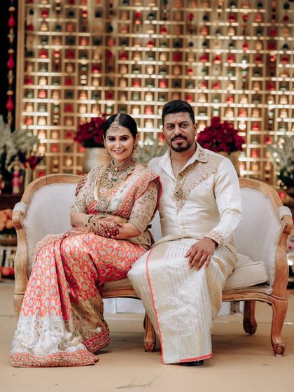 A formal portrait of a couple seated on a vintage sofa. Their coordinated outfits, designed by us, are perfect for creating lasting memories.