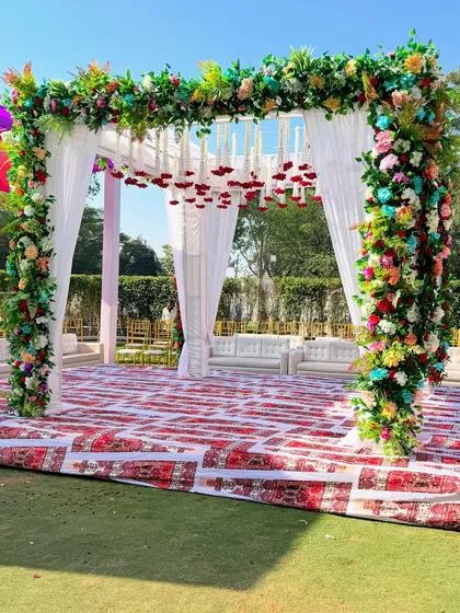 Another view of the colorful floral mandap, showing the printed carpet and the comfortable white sofas for seating.