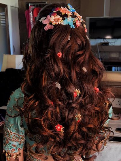 A colorful Sangeet look. Curls can never disappoint, and when adorned with a variety of colorful floral clips, they create a fun and festive hairstyle ready for a party.