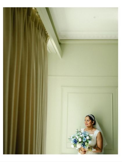 An elegant bridal portrait by a window. The soft, natural light and minimalist background create a serene and sophisticated image.