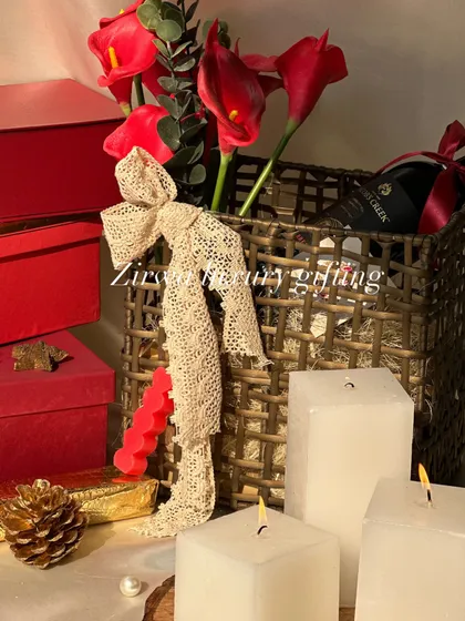 Wrap up joy and warmth this Christmas. This hamper, featuring red flowers, a bottle of wine, and white candles, creates a cozy and festive holiday vibe.