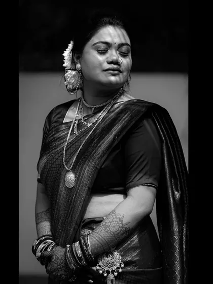 A stunning black and white portrait of a Maharashtrian bride. The play of light and shadow across her face highlights her traditional jewelry and serene expression, creating a timeless and soulful image.