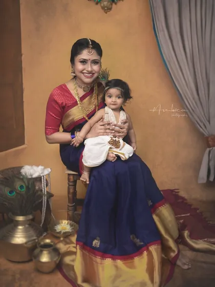 A full-length portrait of mother and son, showcasing the beautiful traditional styling against a warm, artistic backdrop.