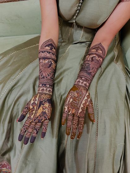 A stunning example of portrait work combined with peacock motifs. The bride's portrait is on one hand and the groom's on the other, symbolizing their union.