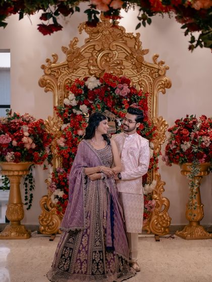 A classic couple portrait against a stunning floral backdrop. The opulent decor complements their elegant engagement outfits.