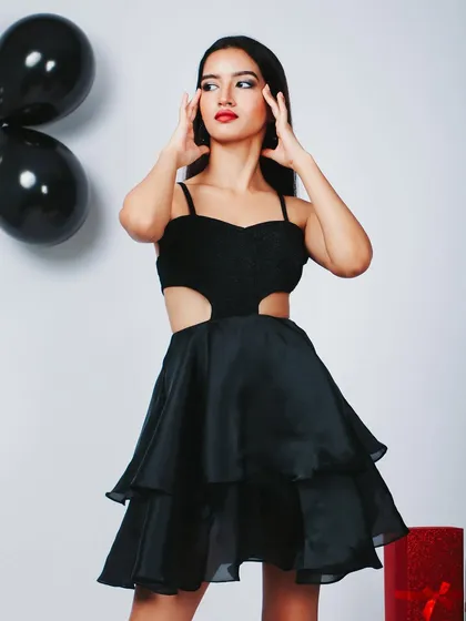 A fun and flirty party dress shoot. The pose is playful and the lighting is bright and celebratory.