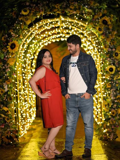 The sunflower-adorned light arch provides a cheerful and bright backdrop for this couple's night-time photo.