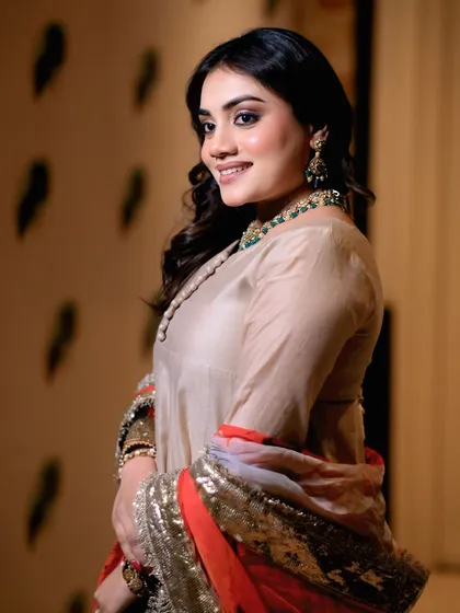 A graceful over-the-shoulder pose by a model. This angle highlights the outfit's sleeves and the model's elegant posture.