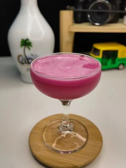 A finished Strawberry Colada, ready to serve. It's a blend of white coconut rum, strawberry syrup, coconut milk, and cranberry juice, perfect for a summer party.