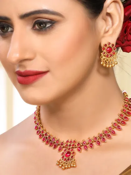 A close-up on a model wearing a traditional ruby-studded necklace set. The rich red of the stones and lipstick creates a bold, festive look, ideal for showcasing special occasion and bridal jewellery.